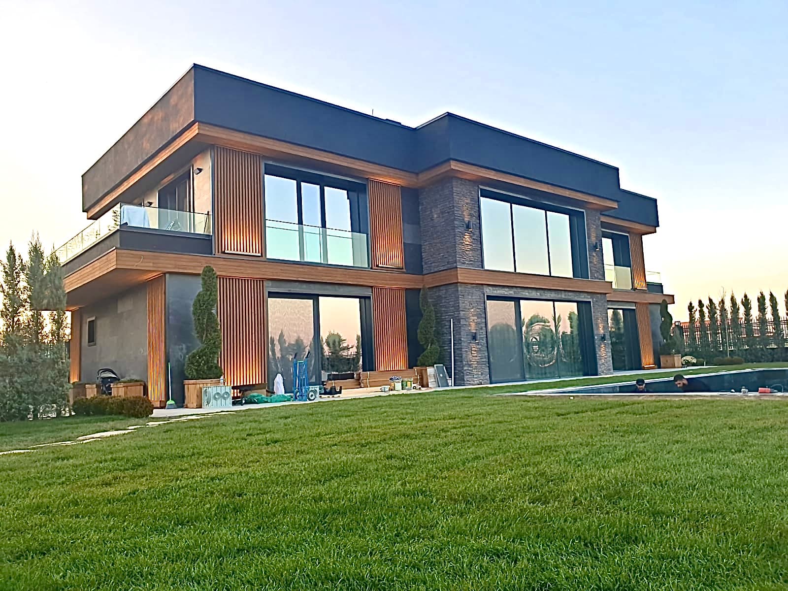 Constructed villa with timber slats, stone cladding, and expansive lawn