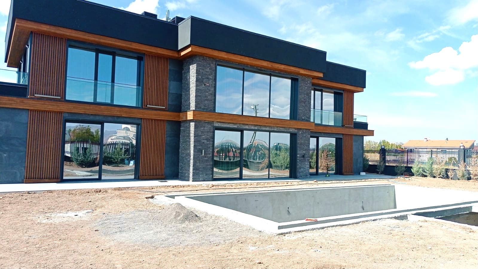 Side elevation showing stone and wood facade with pool foundation under construction