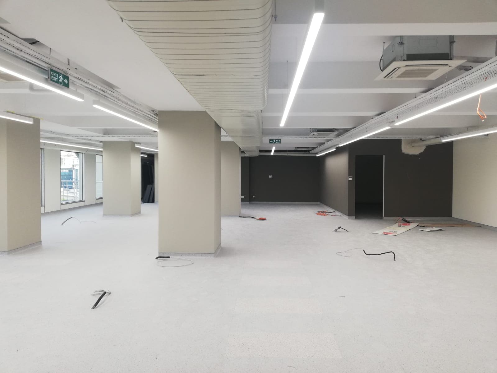 Açık kat planı inşaat sırasında şekilleniyor — kolonlar, aydınlatma ve koyu vurgu duvarları beliriyor.