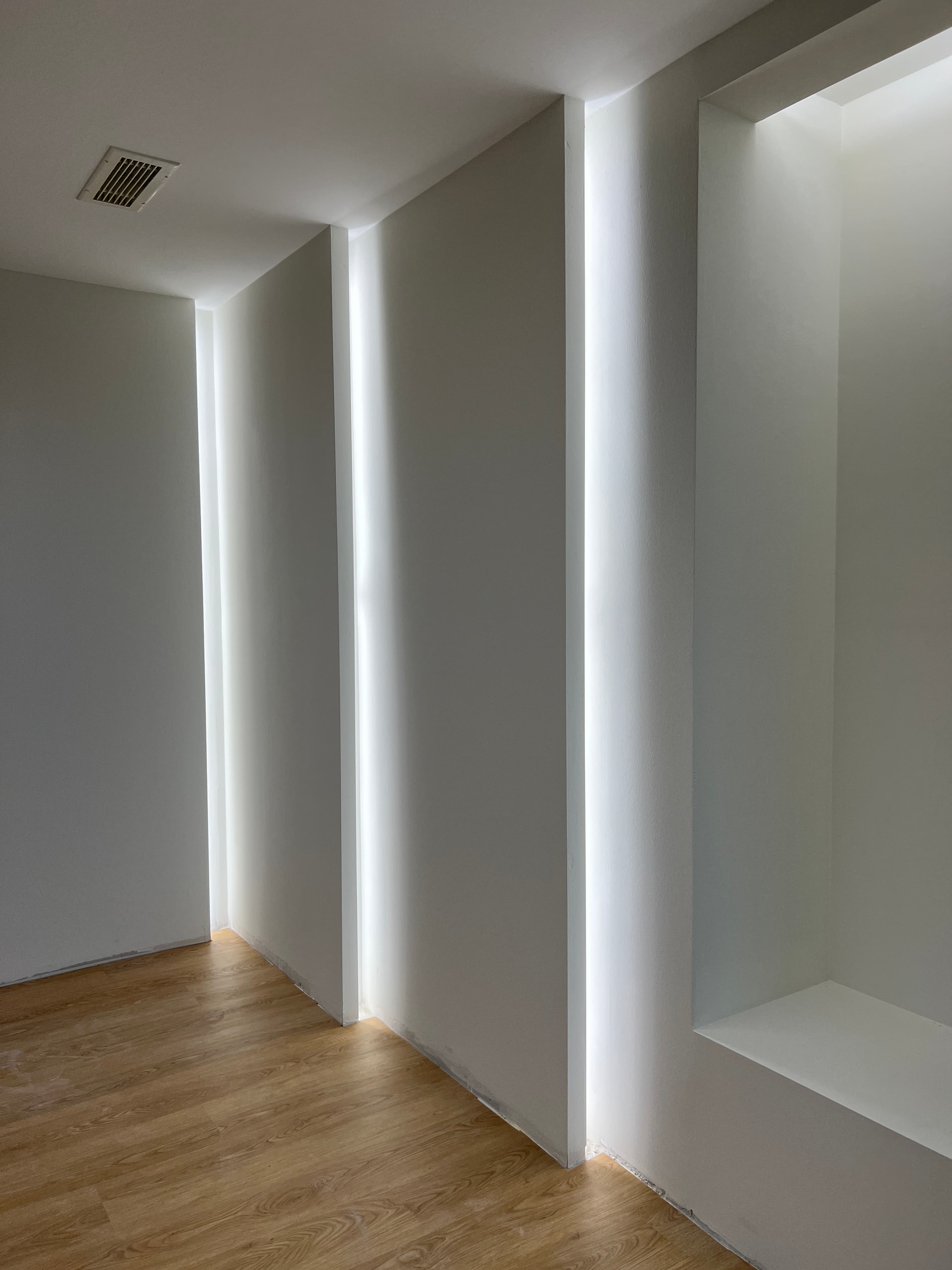 Close-up of recessed ceiling detail with LED strip lighting and oak floor
