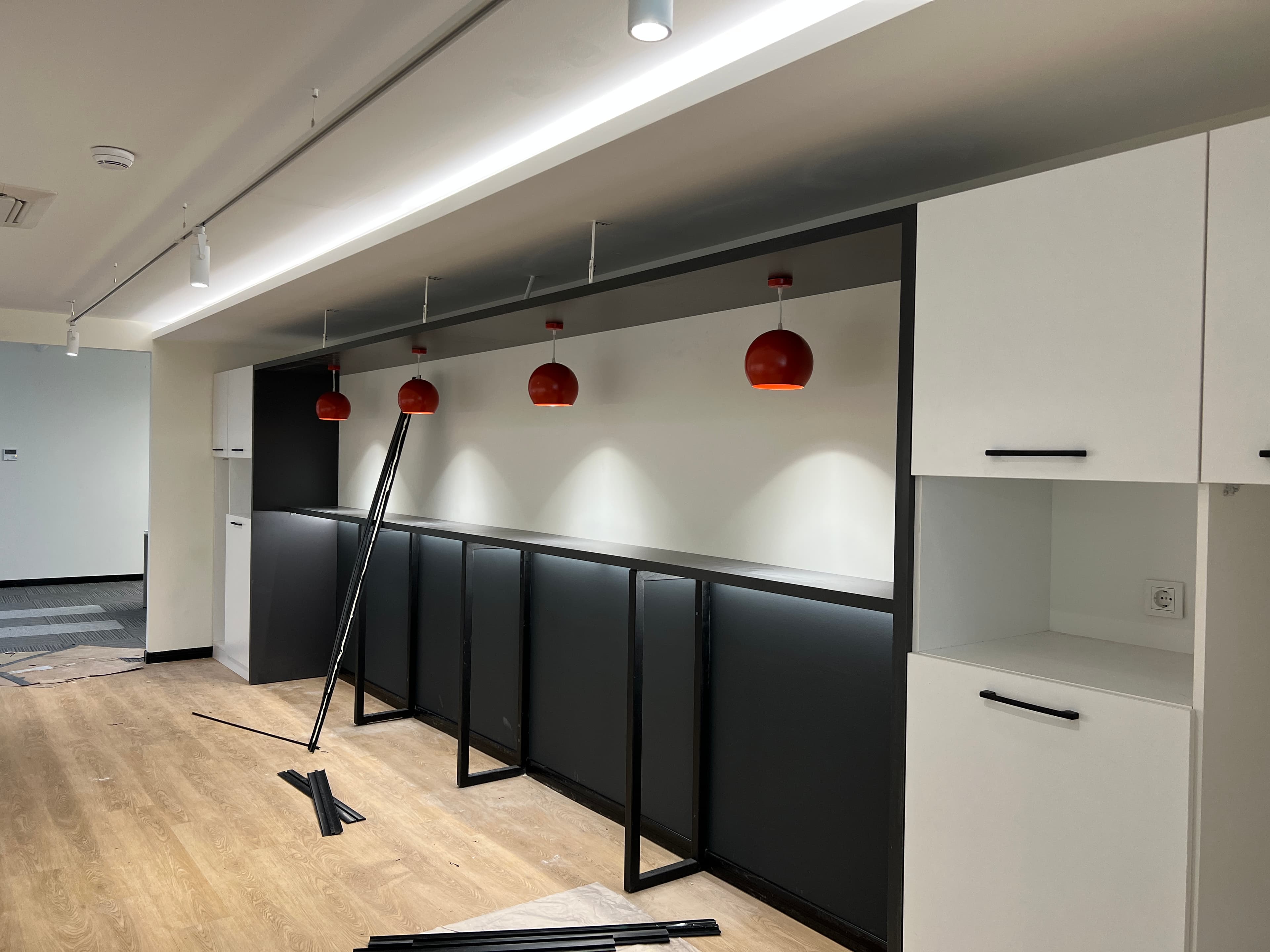 Mola alanı tamamlanmaya yaklaşıyor — siyah bar tezgahı ve kırmızı sarkıt lambalar sosyal merkezi tanımlıyor.