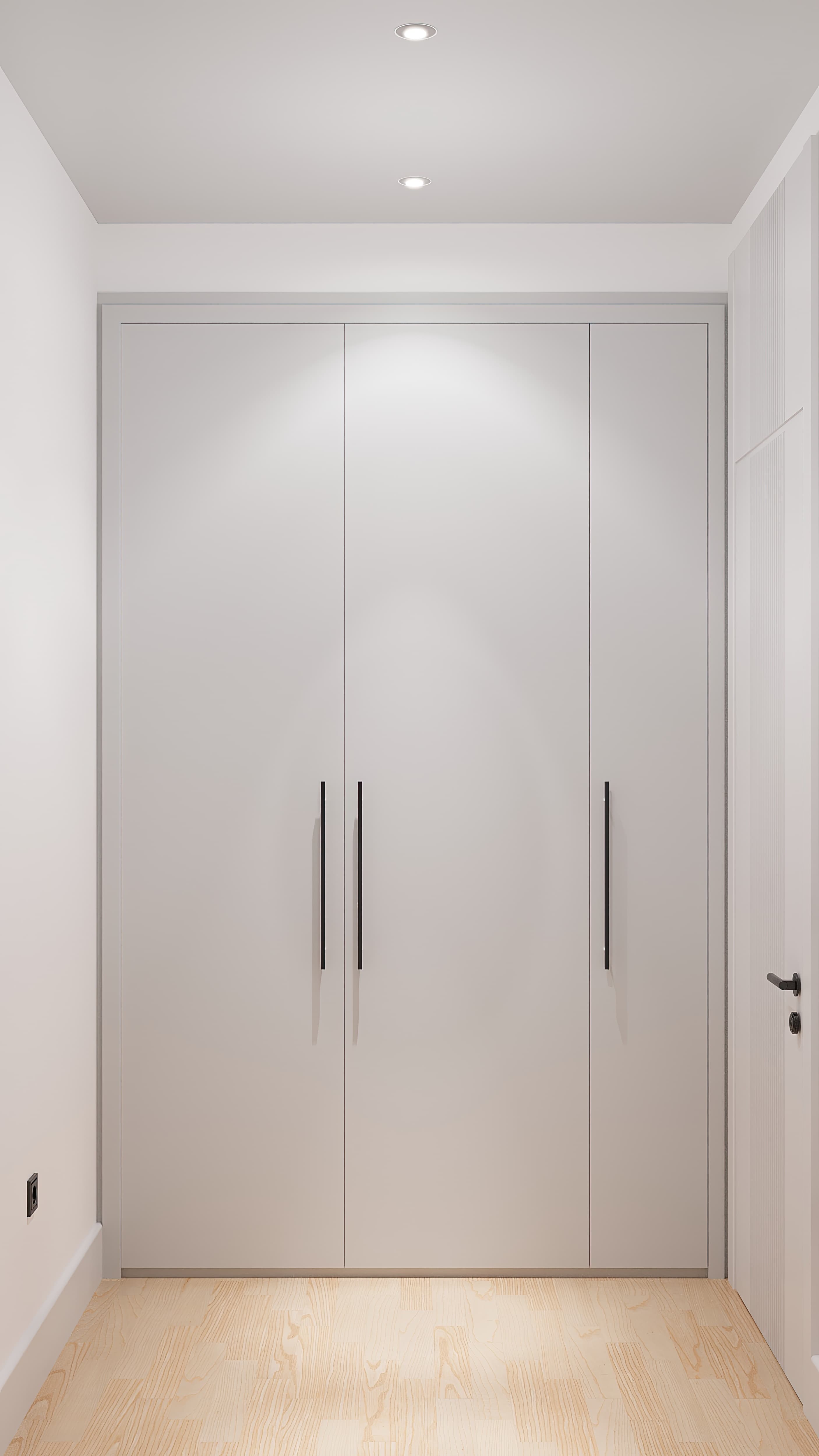Built-in white wardrobe with black bar handles in a narrow hallway